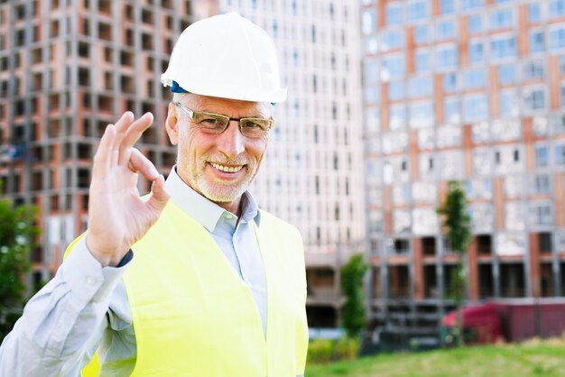 Smiley old man with helmet showing approval