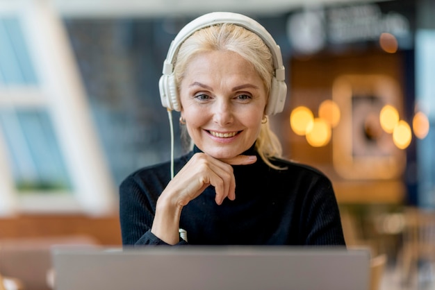 Smiley older woman on a conference with headphones