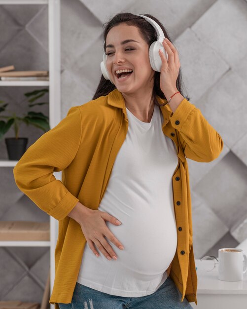 Smiley pregnant woman enjoying music on headphones