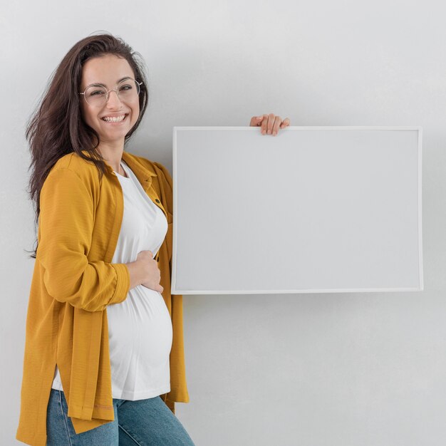 Smiley pregnant woman holding whiteboard