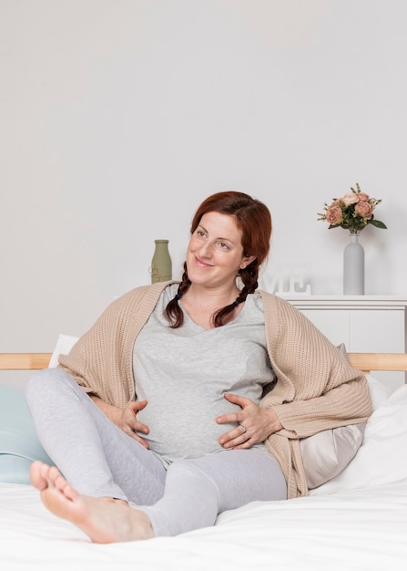 Smiley pregnant woman laid in bed