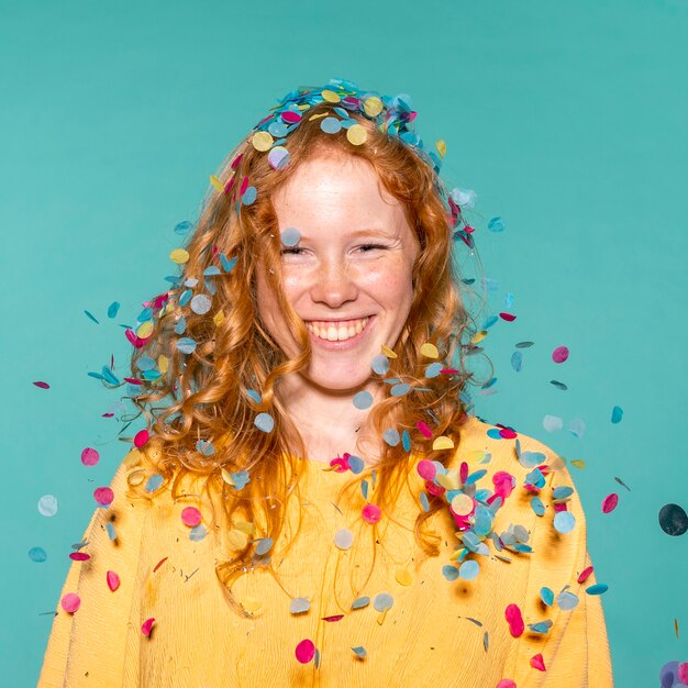 Smiley redhead woman partying with confetti in her hair