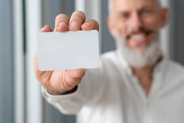 Smiley senior man holding blank business card