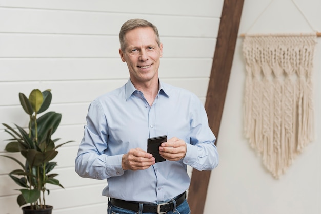 Free photo smiley senior man holding his phone