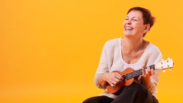 Smiley senior woman playing guitar