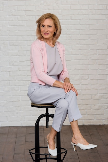 Smiley senior woman posing on black chair