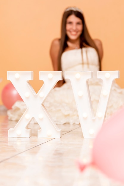 Free photo smiley teenage girl celebrating her quinceañera with fun decoration