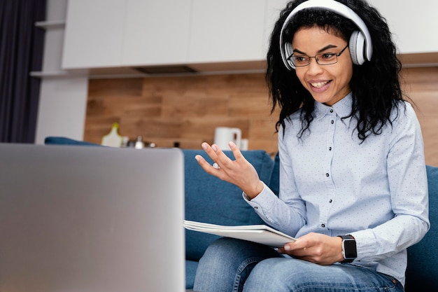 Smiley teenage girl with headphones and laptop during online school