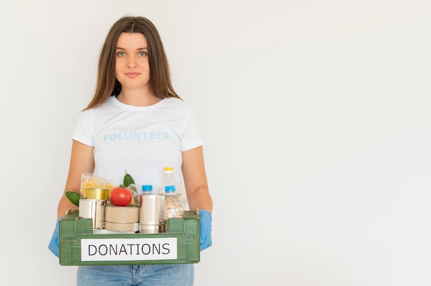 Free Photo smiley volunteer with gloves holding box of food donations with copy space