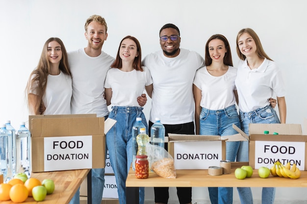 Free Photo smiley volunteers posing next to boxes for donation