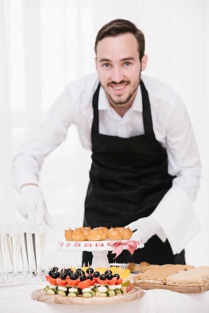 Free photo smiley waiter with food and drinks on a table