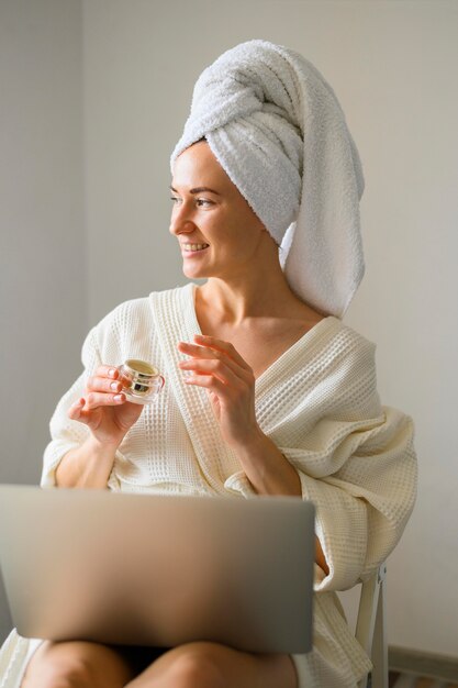 Smiley woman applying cream on her face at home