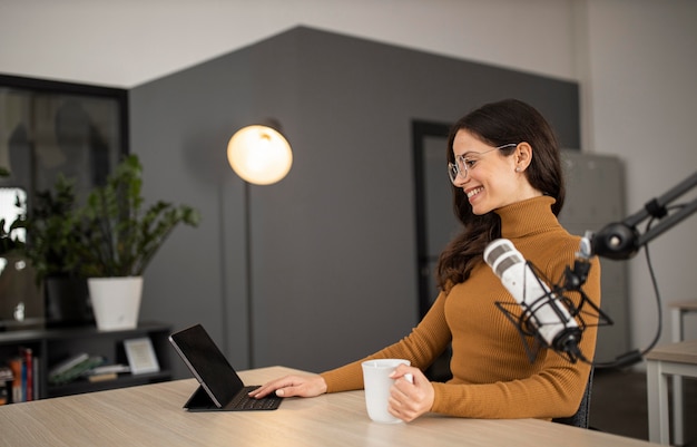 Smiley woman broadcasting on radio with tablet