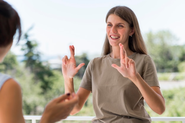 Free photo smiley woman communicating through sign language while outdoors