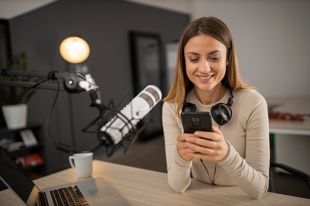 Smiley woman doing radio with microphone and smartphone