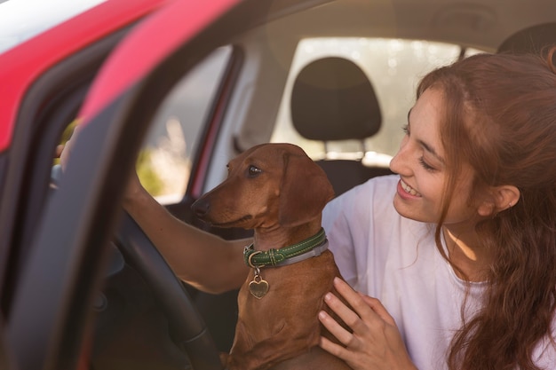 Free Photo smiley woman driving with dog close up