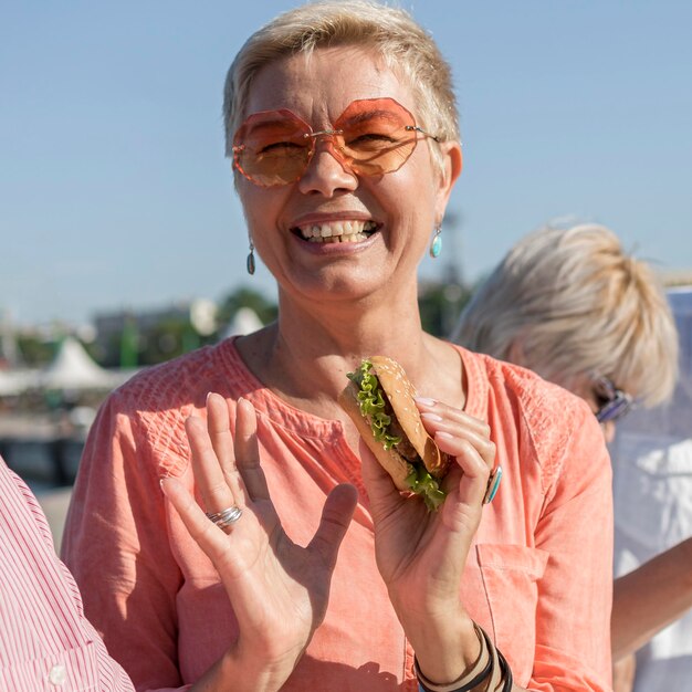 Smiley woman enjoying a burger outdoors