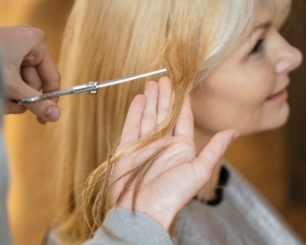 Smiley woman getting a haircut at home with hairdresser