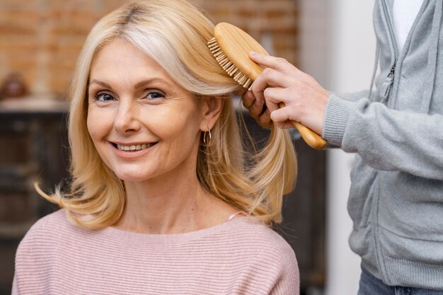 Smiley woman getting her hair brushed at the salon by beautician