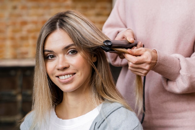 Smiley woman getting her hair straightened at home