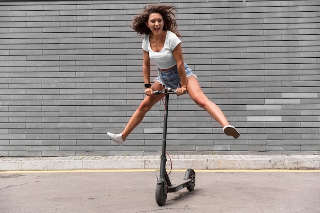 Smiley woman having fun with scooter outdoors