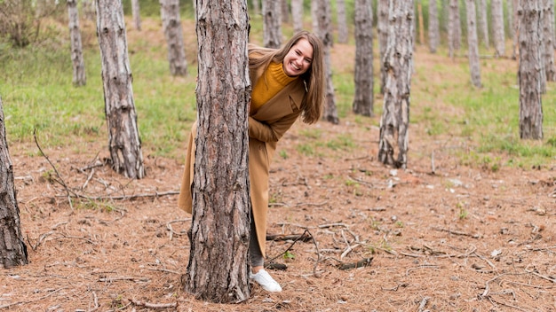 Free Photo smiley woman hiding behind a tree