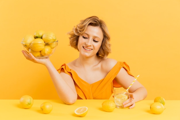 Free photo smiley woman holding bowl with lemons