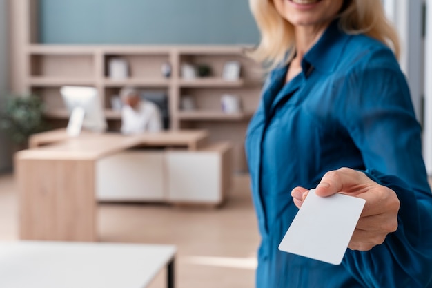 Free photo smiley woman holding business card at work