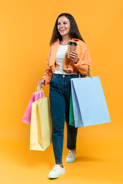 Smiley woman holding cup of coffee and lots of shopping bags