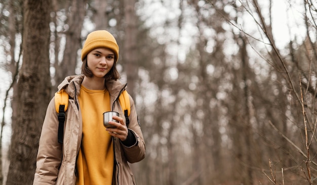 Smiley woman holding cup in forest