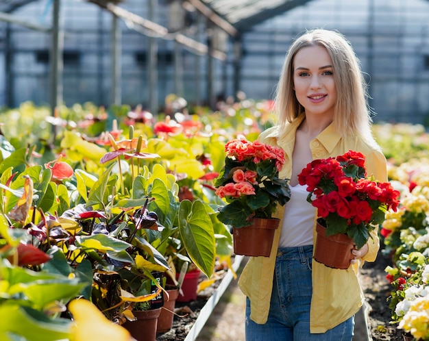 Free photo smiley woman holding flower pots