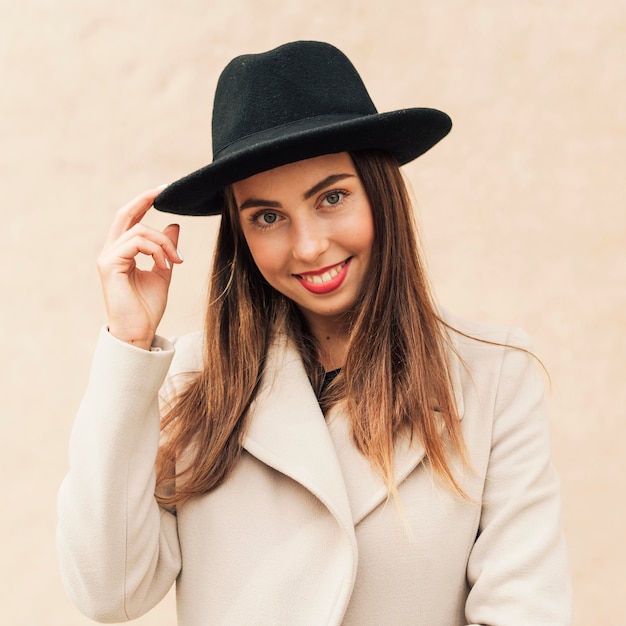 Free photo smiley woman holding her hat