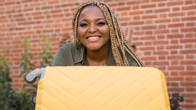 Smiley woman holding her yellow luggage