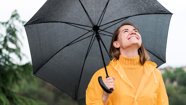 Free photo smiley woman holding an open black umbrella