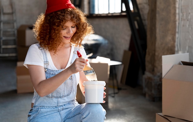 Smiley woman holding paintbrush and bucket for new home decoration