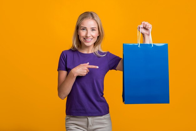 Smiley woman holding and pointing at shopping bag