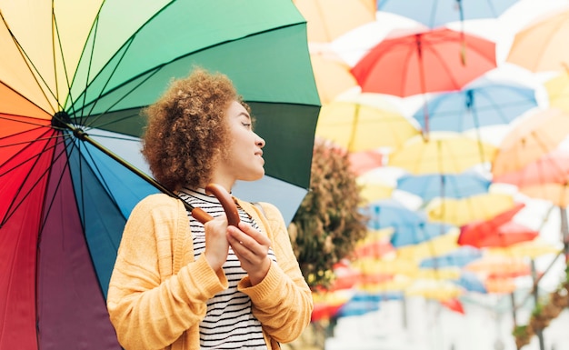 Free photo smiley woman holding a rainbow umbrella with copy space