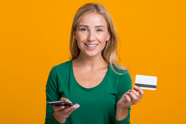 Free photo smiley woman holding smartphone and credit card