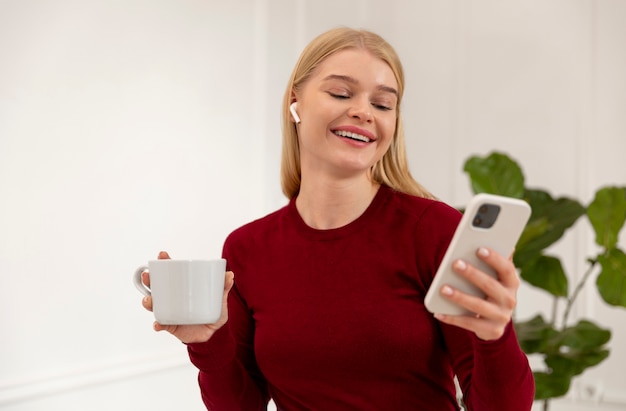 Smiley woman holding smartphone medium shot