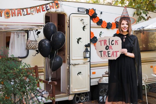 Free photo smiley woman holding trick or treat sign