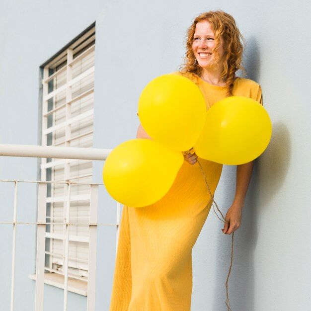 Smiley woman holding yellow balloons