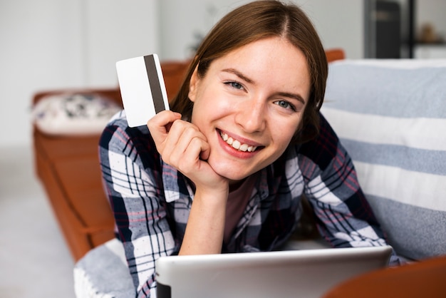 Free photo smiley woman looking at the camera and holding a credit card