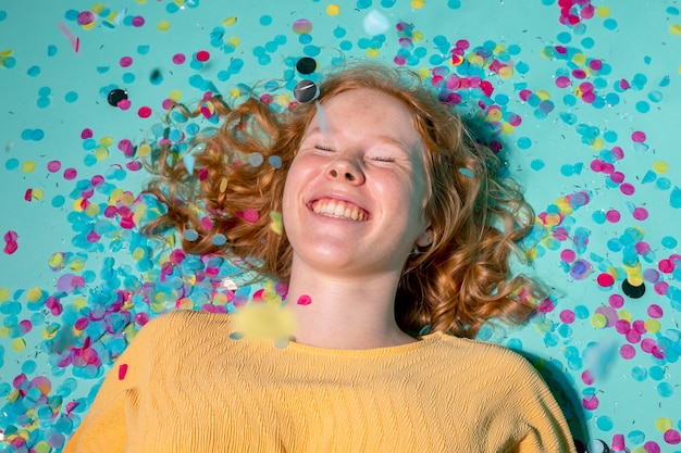 Free photo smiley woman lying on the floor with confetti around her