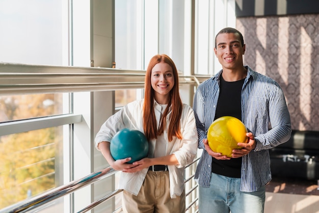 Free photo smiley woman and man holding colorful bowling balls