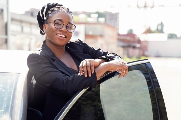 Smiley woman posing next to her car