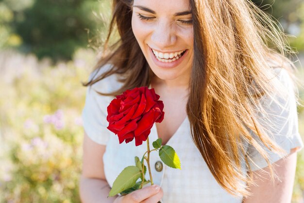 Smiley woman posing while holding rose