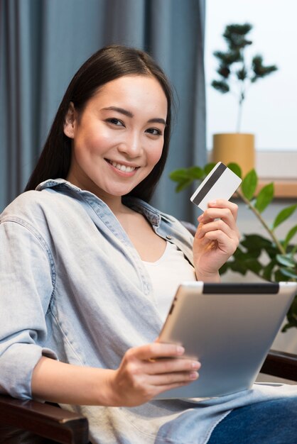 Smiley woman posing while holding tablet and credit card