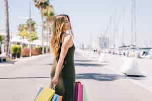 Free photo smiley woman posing with bags and palm trees