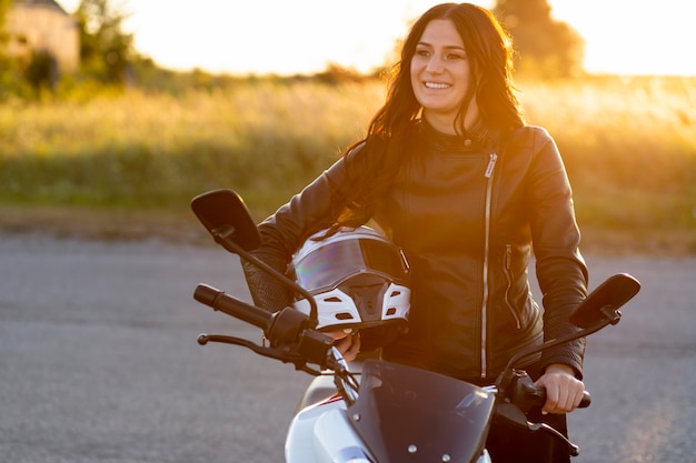 Smiley woman posing with helmet on her motorcycle