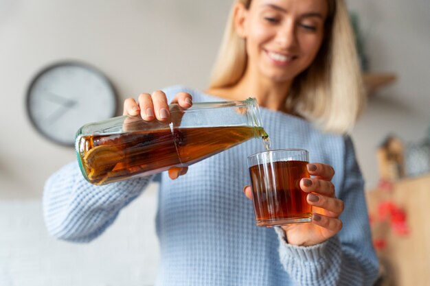 Smiley woman pouring kombucha low angle